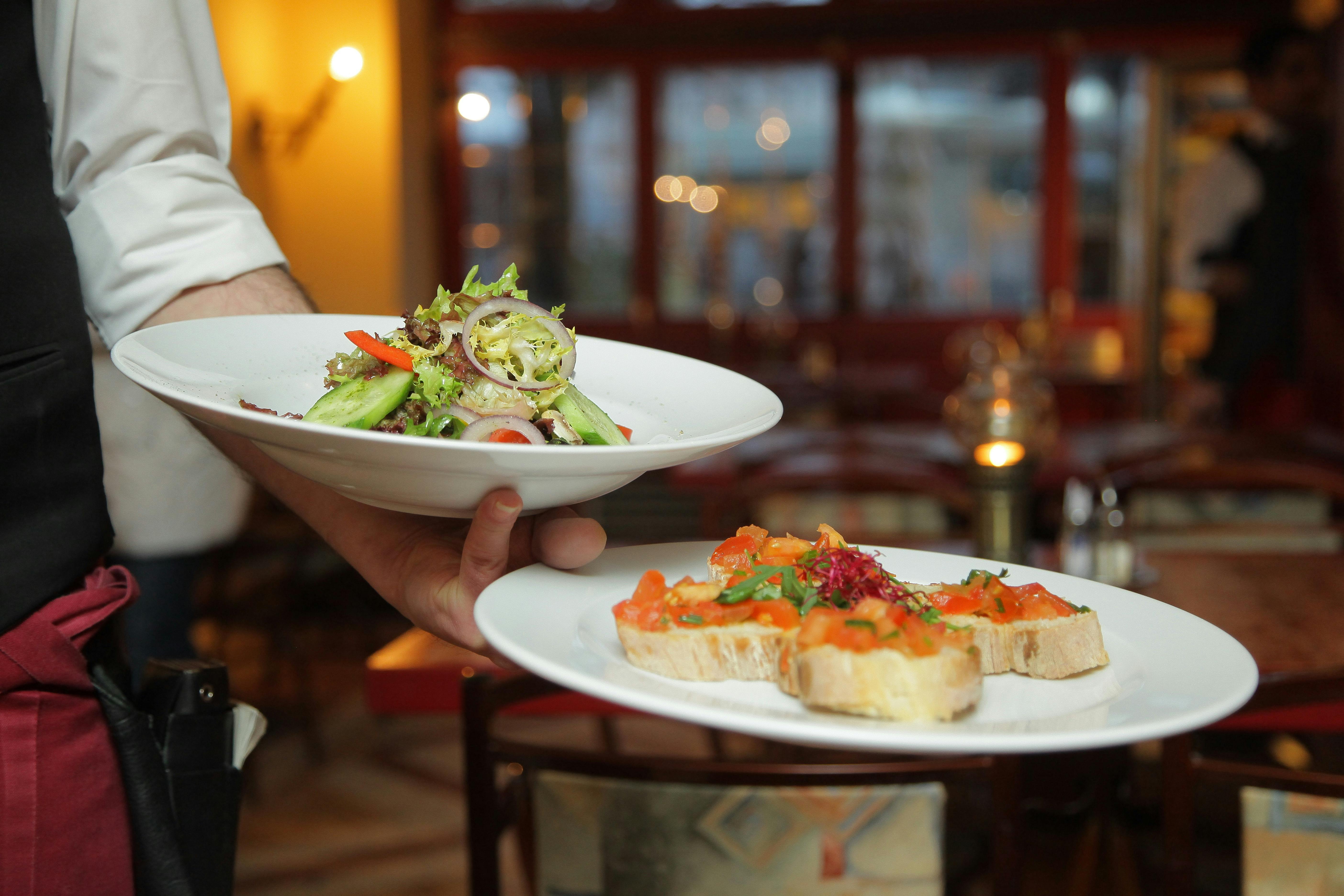 Appetizers at a restaurant, including salad and bruschetta, as a free sign-up incentive for a restaurant loyalty program.